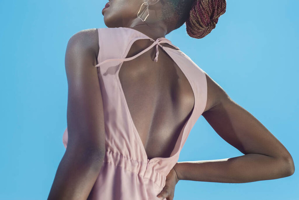 Αφρικανική μοδάτη κοπέλα με καλοκαιρινή ροζ φόρμα, με μαύρη τσάντα, μοντέλο που ποζάρει με την πλάτη της πάνω σε γαλάζιο ουρανό. Σχεδιαστής καλοκαιρινά ρούχα σε ένα μαύρο νεαρό κορίτσι της μόδας ενάντια σε ένα δρόμο - Φωτογραφία, εικόνα
