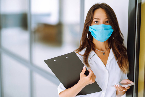 Office woman  worker  in sterile mask work in the office during an epidemic. COVID-19. Business concept.  - Photo, Image