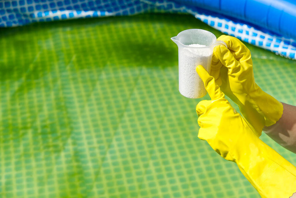 adición de cloro en polvo para la piscina para eliminar las algas y desinfectar el agua. concepto inflable del cuidado de la piscina
. - Foto, Imagen
