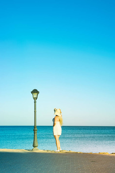Mujer rubia joven en un sombrero camina cerca de la playa
. - Foto, imagen