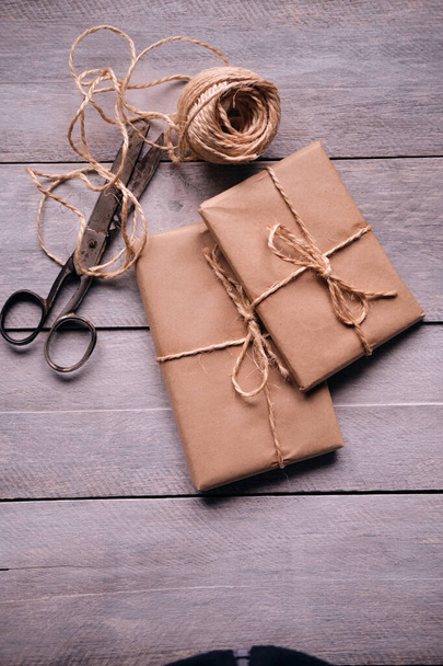 Geschenkpaket aus Kraftpapier, Seil und Schere auf rustikalem Holztisch - Foto, Bild