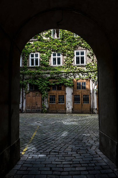 Courtyard Of A Historic Building With Wooden Doors And Ivy Overgrown Walls - Foto, imagen
