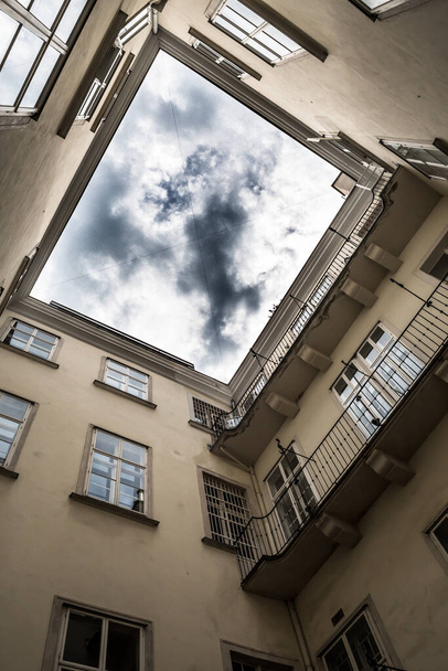 Cortile stretto con vista fino al cielo nuvoloso di un edificio storico - Foto, immagini