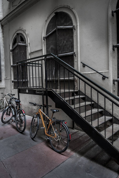 Vecchie biciclette parcheggiate su scale di ferro sotto l'edificio storico con porte chiuse nella città interna di Vienna in Austria - Foto, immagini