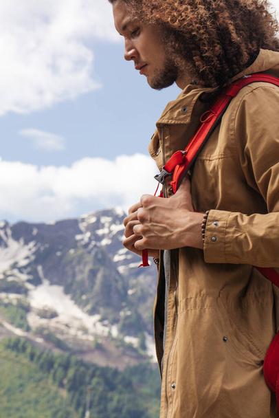 Man Traveler with red backpack relaxing outdoor with rocky mountains on background - Фото, зображення