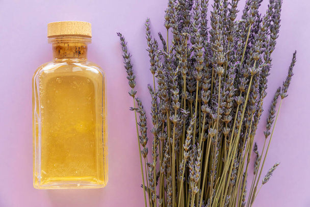 Lavender essential oil, a bottle and lavender bouquet on violet background - Foto, Imagem