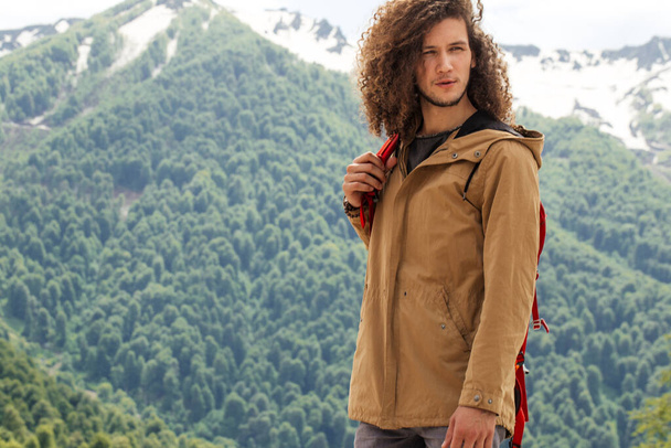 Man Traveler with red backpack relaxing outdoor with rocky mountains on background - 写真・画像