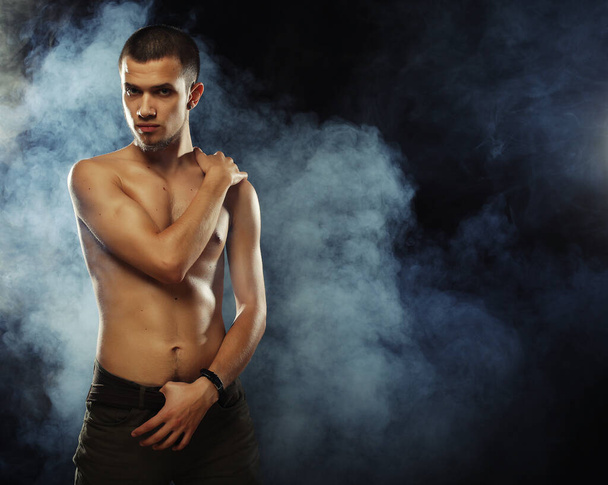Portrait of a muscular male model against dark background with - Фото, изображение