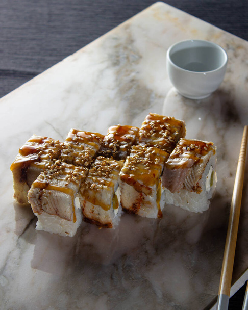 Sushi. Una porzione di panini giapponesi freschi su una tavola di marmo con salsa di soia, wasabi e zenzero sottaceto. - Foto, immagini