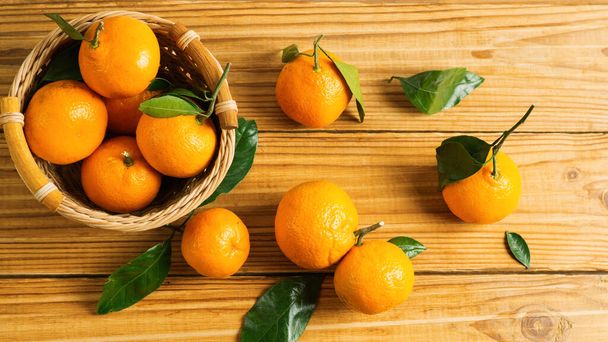Delicious bright ripe tangerines with leaves on a wooden table - Fotó, kép