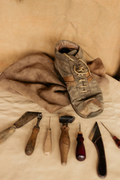 Een oude bruine herenschoen met schoenmaker die op leder ligt. Klokkenspel.  - Foto, afbeelding