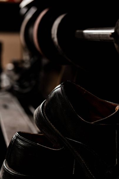 Чоловіче взуття проти шліфувальної машини, темна атмосфера з блискучими відблисками
.  - Фото, зображення