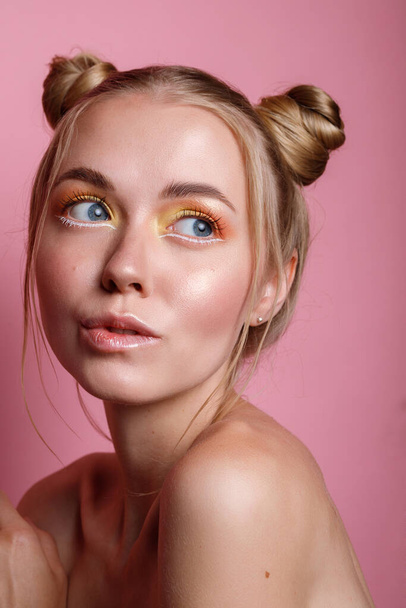 Portrait d'une fille blonde avec un maquillage d'été sur un fond rose - Photo, image