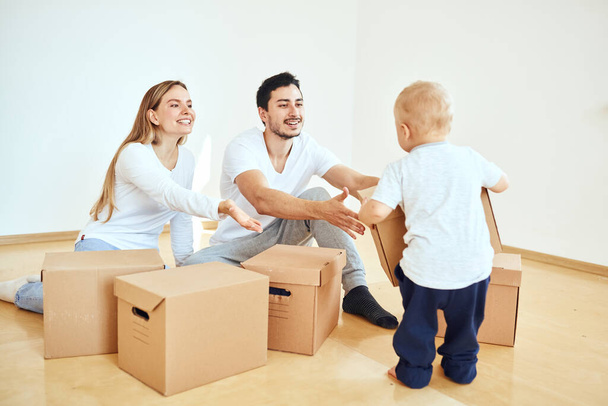 Familia con niño desempacando cajas de cartón móviles en un nuevo hogar - Foto, imagen