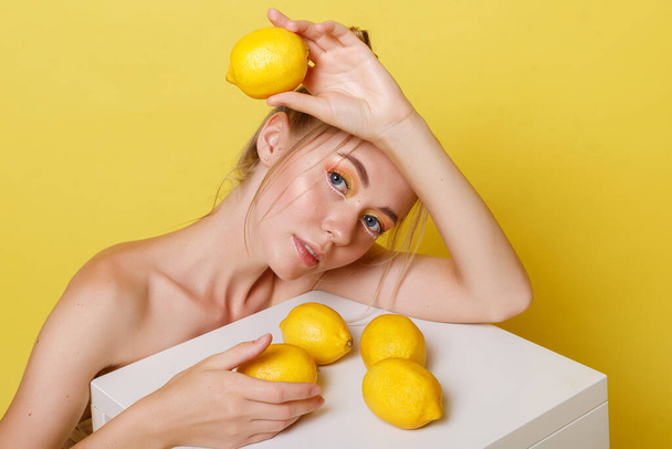 model with lemons on a yellow background - Photo, Image