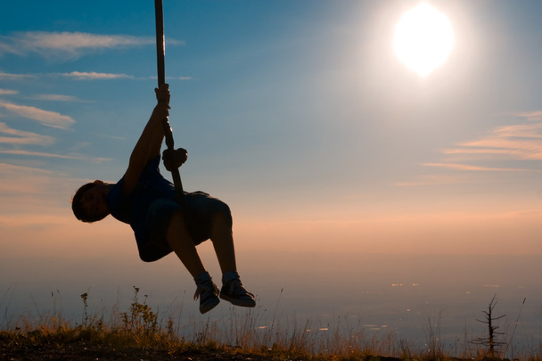 Silhouette of a boy playing with a tyrolean traverse - Fotó, kép