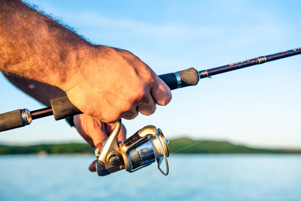 fishing rod in hand man close-up. Shallow depth of field, soft focus  - Foto, Bild
