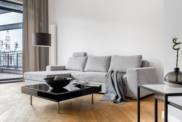Living room with simple, gray corner sofa and black coffee table - Fotó, kép
