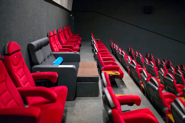 VIP καρέκλα σε έναν άδειο κινηματογράφο ανάμεσα σε κόκκινες μαλακές καρέκλες. - Φωτογραφία, εικόνα