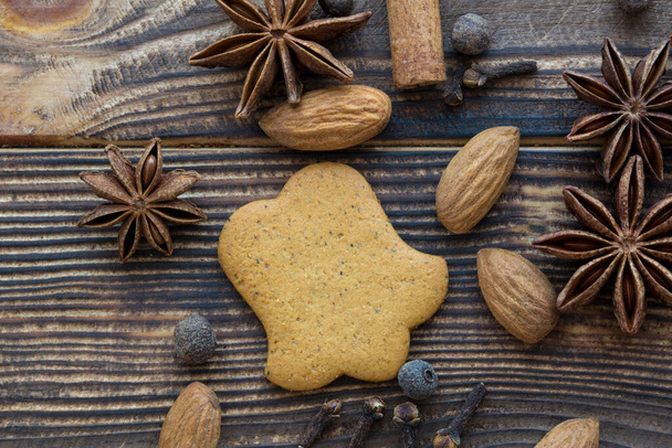 Gingerbread cookies with spices and almonds on brown wooden background. Bell shape, top view.  - Foto, afbeelding