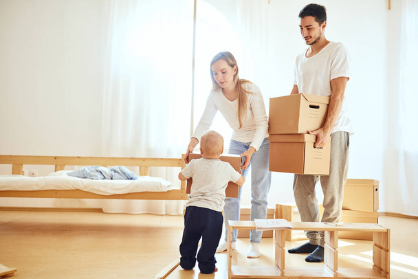 little boy carrying moving box, parents on blurred background. Moving concept - Photo, Image