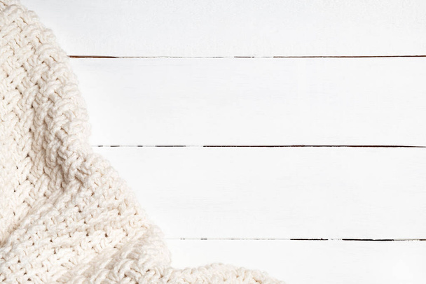 Ζεστό ανοιχτό μπεζ μάλλινο ύφασμα σε λευκό ξύλινο φόντο με χώρο αντιγραφής. Άνετο και μαλακό φόντο χειμώνα - Φωτογραφία, εικόνα