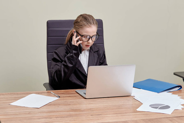 Girl with glasses as a company director. The girl is sitting at a table - Photo, Image