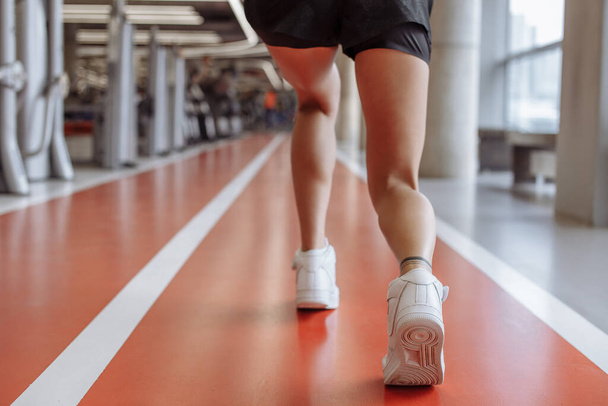 female legs and running shoes of sport woman jogging in fitness centre on track - Foto, immagini