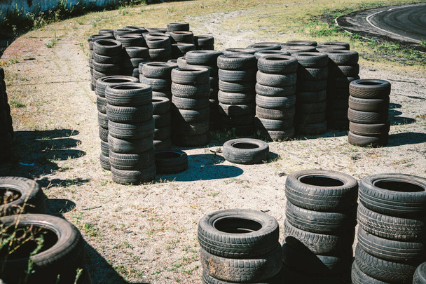 Muitos pneus usados velhos do carro empilhados em cima um do outro no complexo de esportes do automóvel. Aterro industrial para o processamento de resíduos de pneus e pneus de borracha. Velhas rodas de borracha. Pneus no autódromo
. - Foto, Imagem