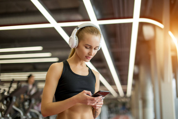 Active blond woman sportswear using smart phone in gym. - Fotó, kép