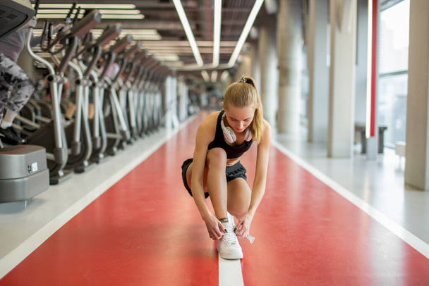 girl tying shoelaces at fitness gym before running exercise workout for cardio - Fotoğraf, Görsel