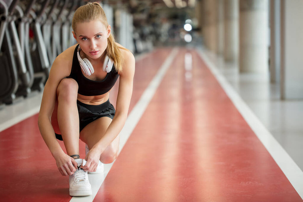 girl tying shoelaces at fitness gym before running exercise workout for cardio - Valokuva, kuva