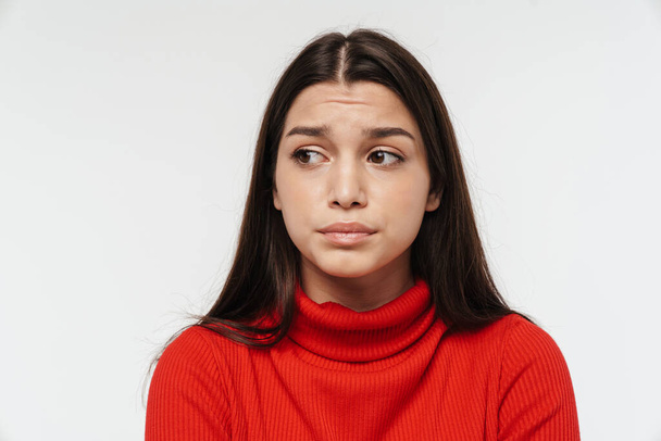 Portrait of a pretty upset young brunette woman wearing casual clothing isolated over white background, looking away - Fotó, kép