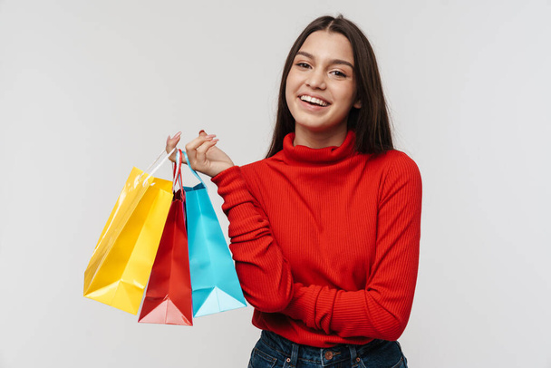 Photo of happy brunette woman laughing while holding shopping bags isolated over white wall - Foto, immagini