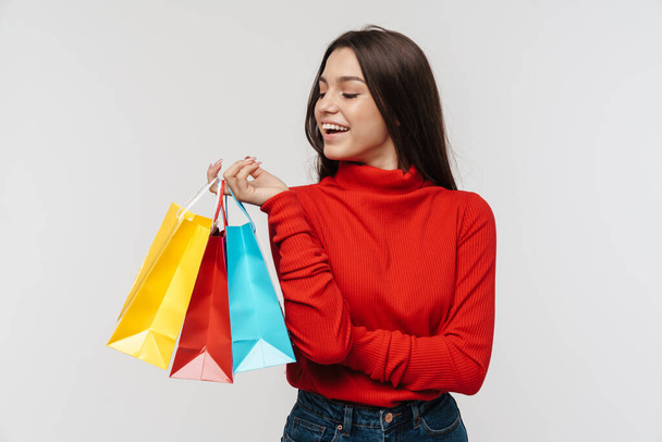 Photo of happy brunette woman laughing while holding shopping bags isolated over white wall - Φωτογραφία, εικόνα