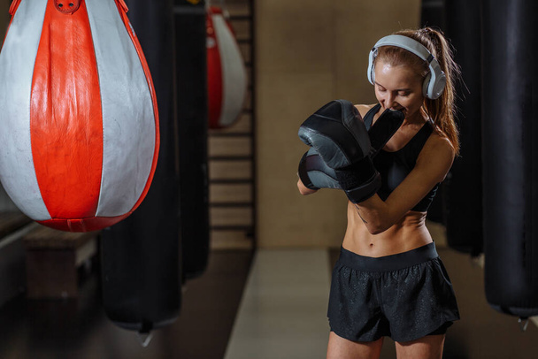 Female fighter wearing hand gloves prepare for exercise on punching bag - Foto, Imagem