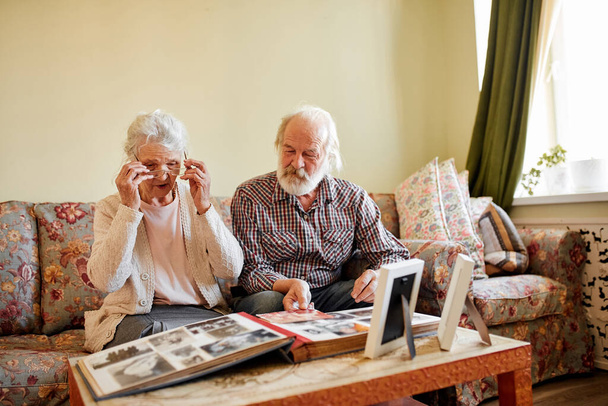 Seniors looking at their photo album at home - Foto, afbeelding