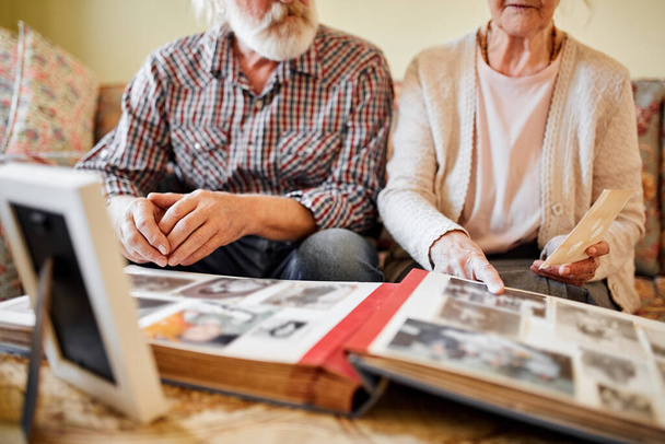 Seniors looking at their photo album at home - 写真・画像