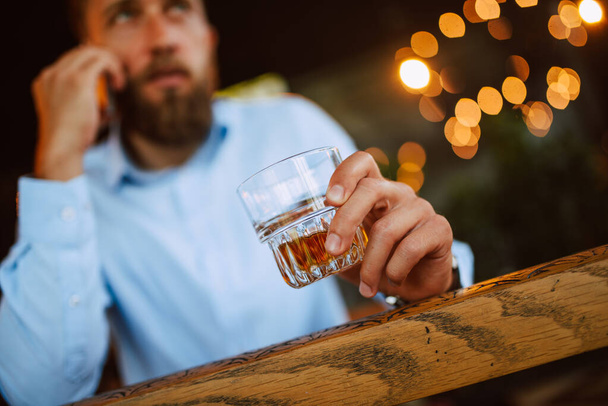 Valkoihoinen mies puhelimen ja lasin kanssa baarissa - Valokuva, kuva