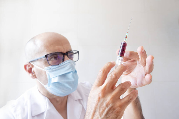 medico con una siringa di sangue in mano che tocca l'aria - Foto, immagini
