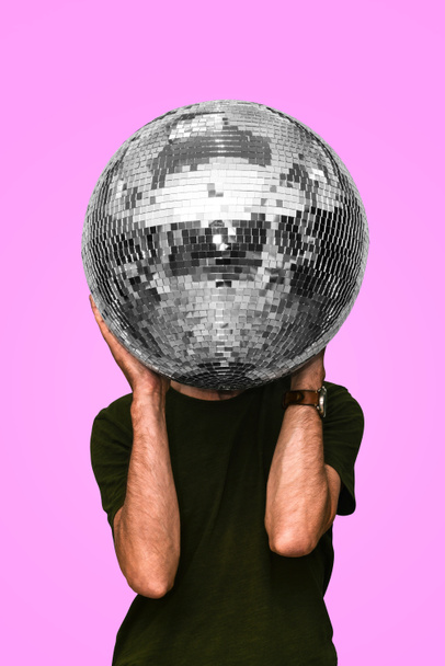 De man heeft een discobal. Spiegelbal. Concept van een nachtclubfeest, clubleven. Uitgaansleven - Foto, afbeelding