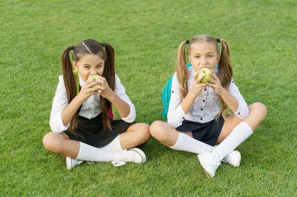 Schoolgirls eating apples relaxing schoolyard, healthy lunch concept - 写真・画像