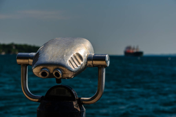 Visualizador binocular com navio de carga em St. Lawrence River em segundo plano
 - Foto, Imagem