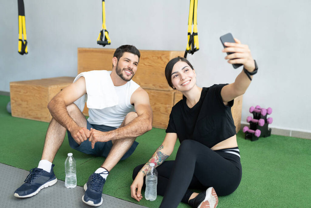 Mosolygó spanyol fiatal pár csinál szelfi keresztül smartphone fitnesz stúdió - Fotó, kép