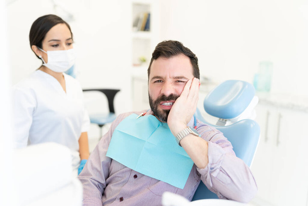 Mittlerer erwachsener Mann leidet unter Zahnschmerzen während der Zahnbehandlung - Foto, Bild