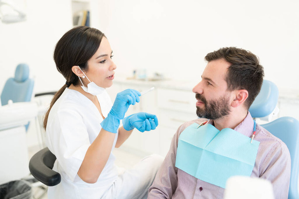 Médica examinando o homem adulto médio sentado na cadeira na clínica odontológica
 - Foto, Imagem