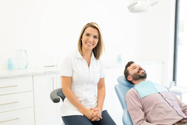 Καυκάσια γυναίκα οδοντίατρος με ενήλικο άντρα στην κλινική - Φωτογραφία, εικόνα