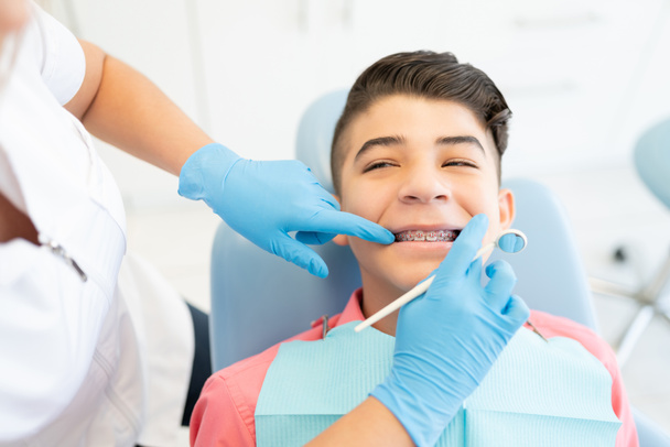 Odontóloga examinando adolescente usando aparatos ortopédicos
 - Foto, imagen