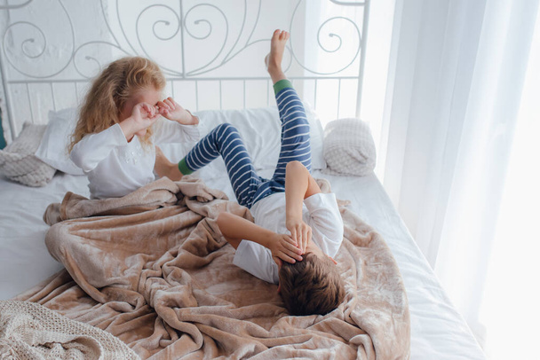 Little siblings waking up in cozy bed - Foto, afbeelding