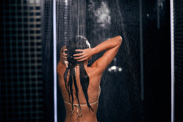 Woman in the shower, back side of young beautiful female under refreshing water - Valokuva, kuva